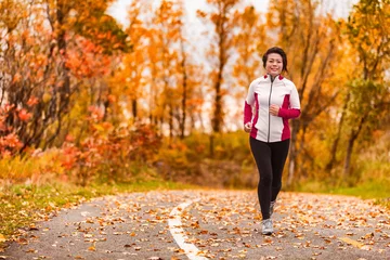 Papier Peint photo Jogging Femme asiatique mature d& 39 âge moyen, active et en bonne santé, faisant de l& 39 exercice pour perdre du poids, faire du jogging dans la forêt d& 39 automne du chemin du parc. Mode de vie d& 39 âge moyen. Dame dans la cinquantaine.