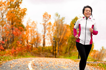 Mature happy middle age woman jogging outside in her 50s. Middle aged Asian chinese girl in her...