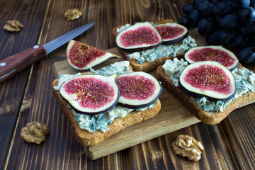 Toasts with blue cheese and figs on the brown cutting board