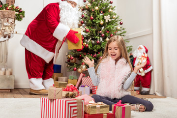 Obraz na płótnie Canvas Cheerful kid receiving gifts from kind Santa