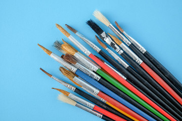 Fototapeta premium Row of artist paint brushes close up on blue background