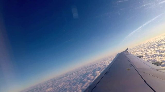 Canted angle shot over wing of airplane as it climbs above the clouds over Montreal, Canada.