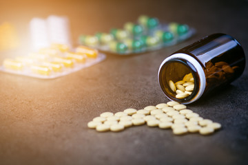 Medicines, supplements in a glass bottle. Pills spilling out from glass bottle. Medicine´s background. Pharmacy. Close up of capsules. Pack of tablets on a black background.
