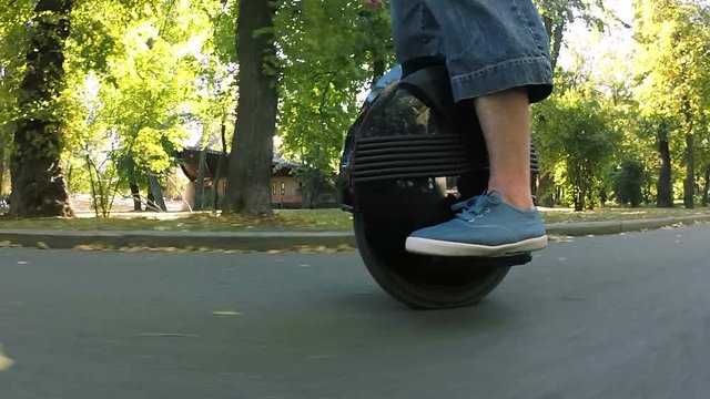 
Feet of man on mono wheel, personal electrical transport in autumn city park. POV  view
