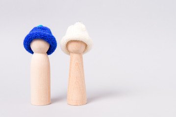 Two miniature wooden figurines in knitted hat.