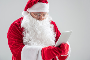 Surprised Santa Claus watching modern tablet