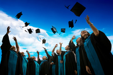 Group of graduates with congratulations throwing graduation hats in the air celebrating.