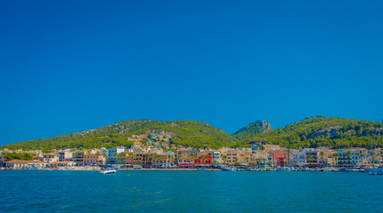 Fototapeta na wymiar Beautiful view of Mallorca balearic islands, with some buildings in the mountain in the horizon, with gorgeous blue water and a beautiful blue sky, in Spain