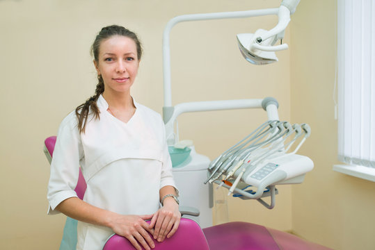 Young female dentist in dental office smiling and looking at camera