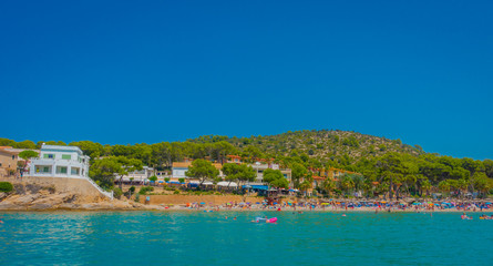 Beautiful sunny day in Sant Elm, with a beautiful blue water in Majorca, with some building in the horizont and people enjoying the weather, in Spain