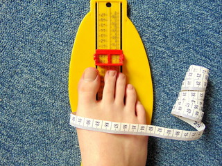 yellow foot measurement device with naked foot upon with measuring tape