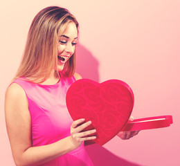 Happy young woman holding a heart shaped box