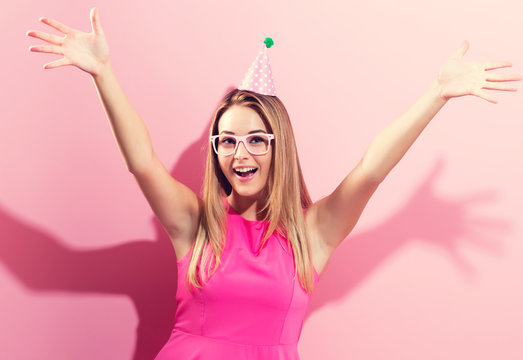 Young woman with party hat on a pink background