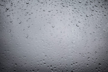 Drops of rain on a grey window glass. Close up   detail of a wet surface water with copy space