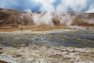 Iceland landscape. Steaming geothermal sources. People walking around and watching geologic features.