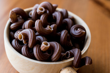 Raw Brown Pasta with Grape seeds in wooden ladle.
