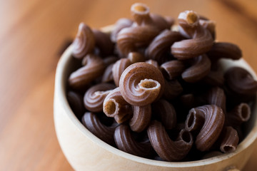 Raw Brown Pasta with Grape seeds in wooden ladle.
