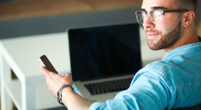 Young man using phone and works on the laptop