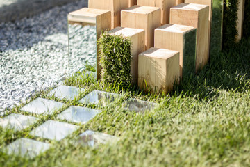 Wooden sculpture with mirrors on the background of grass. Modern design and park architecture. Vertically.