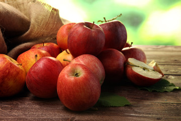 Naklejka na ściany i meble Ripe red apples with leaves on wooden background