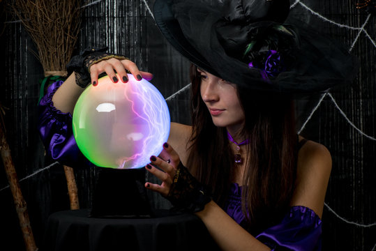a girl in a black hat works as a fortune-teller, looks carefully into the ball of fate