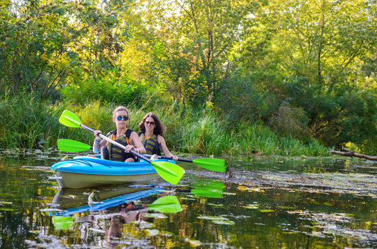 Family kayaking, mother and child paddling in kayak on river canoe tour, active summer weekend and vacation, sport and fitness concept
