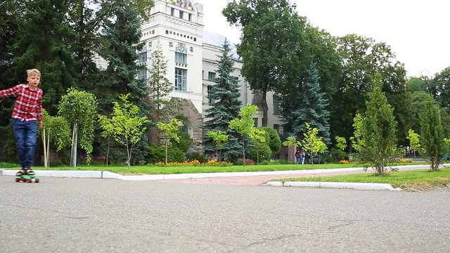 White child learning to skate on green plastic rollerskate in city street. Kid of 10 years has fun on summer or autumn evening. Real time full hd video footage.