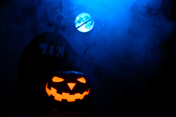 Scary Halloween pumpkin in the background of tombstones and full moon in the fog