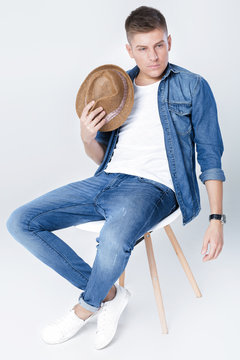 handsome man in denim sits on chair 