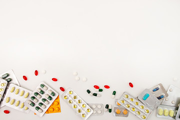 Fototapeta na wymiar Heap of medicine tablets and pills in blisters different colors on white background. Healthcare or medicament addiction concept. Copy space.