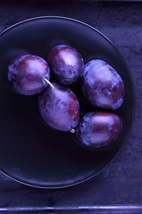 Plums on a black plate for designer