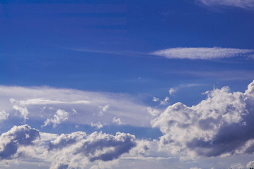 Naklejka na ściany i meble Epic clouds lit by sun on blue sky background
