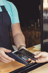 Person paying pay through smartphone using NFC technology in outdoor cafe