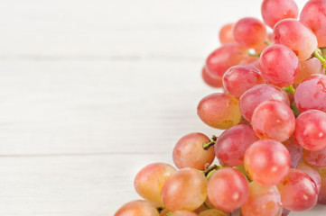 Bunch of fresh ripe pink grapes on old wooden rustic white planks