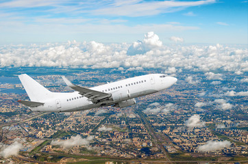Passenger white airplane flies climbing over a large megaopolis, city