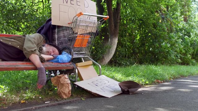 Old poor man living in the streets. No home, no money, drunk man lying on bench sleping.