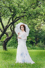 Fototapeta premium Woman in long white dress in summer garden