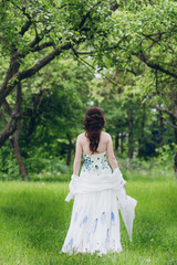 Woman in long white dress in summer garden