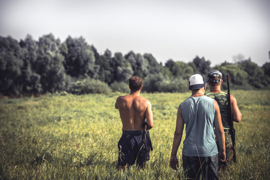 Group of strong male hunters going through rural field with tall grass   during hunting season