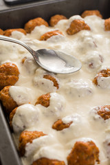 Pouring yogurt on the minced meat meatballs ready for baking