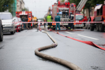 Fire hoses on the background of fire trucks and firefighters at work