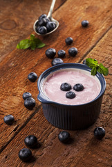 Youghurt with blueberries on a wooden background