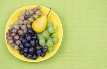 Fresh rose and green grapes and pear. Grapes on a yellow plate