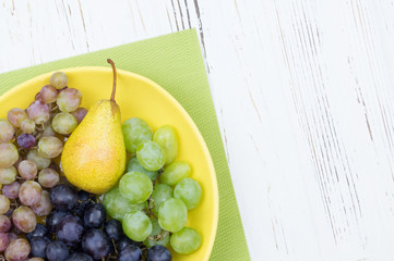 Fresh rose and green grapes and pear. Grapes on a yellow plate