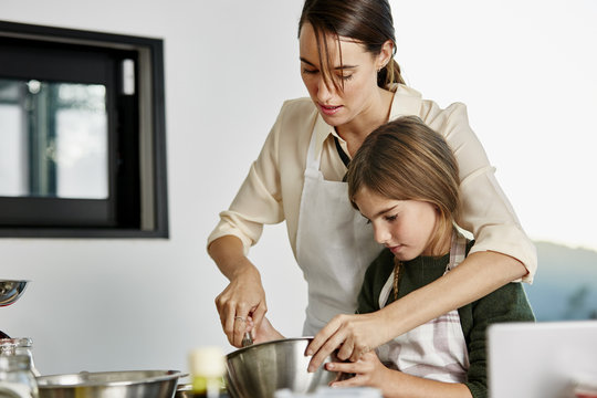 Woman Assisting Daughter In Preparing Cupcake