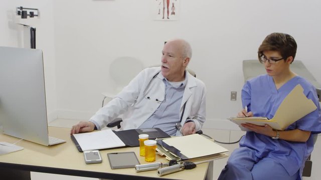 Elderly doctor talking to nurse and taking notes