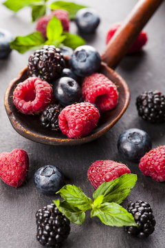 Ripe and sweet berries in vintage wooden spoon on black background