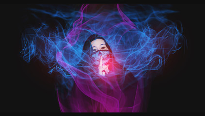 Girl wearing a skull mask with the finger on mouth asking for silence. Dark background with some blue and pink flames made of light painting technique.