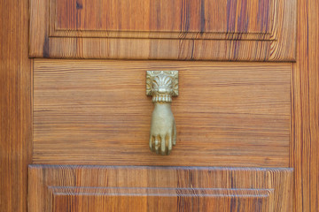 Hand als Türklopfer an einer Haustür