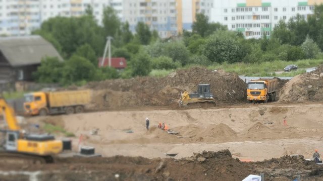Construction vehicles and builders on construction site in a summer season
